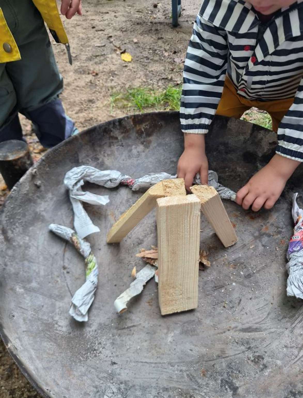 Ein Kind legt Holz in die Feuerschale