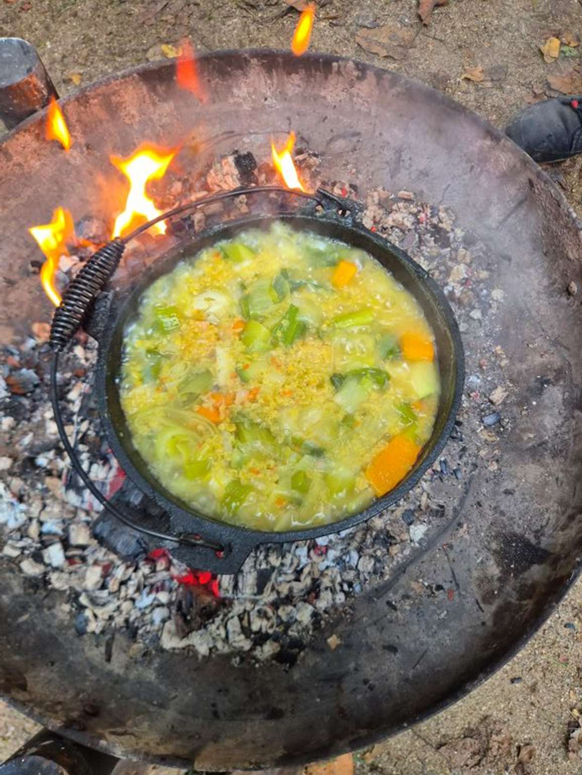 Die Gemüsesuppe kocht im Feuertopf über dem Feuer